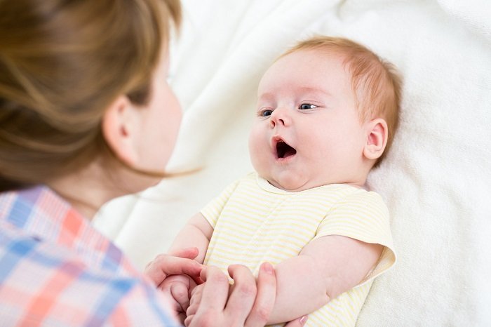 bé sơ sinh nằm trên giường đệm trắng trò chuyện với mẹ, phát triển ngôn ngữ
