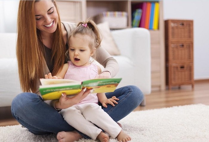 mẹ đọc sách cho con gái trên sàn nhà